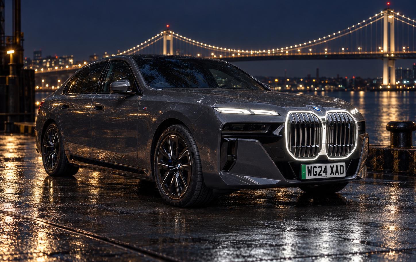 BMW i7 beside an illuminated bridge at night